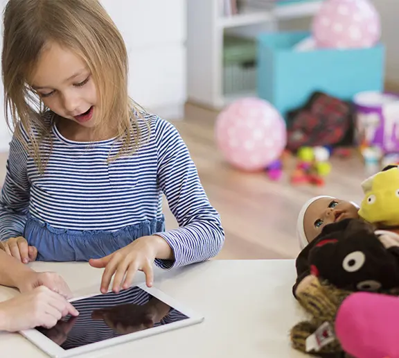 numérique et écologie avec les tout-petits en mobilité erasmus dans une crèche à Malte. L'image montre une petite fille en crèche qui joue sur une tablette numérique à un jeu de sensibilisation à l'écologie.